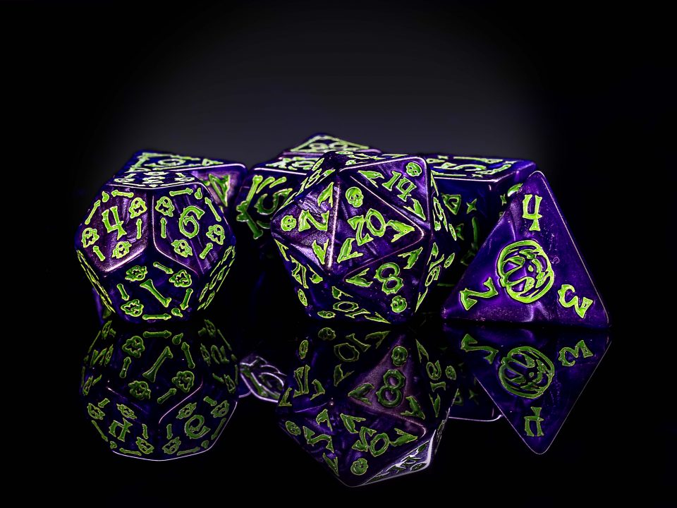 Mehrere violette Würfel mit grünen Zahlen und Knochenmotiven aus Harz.