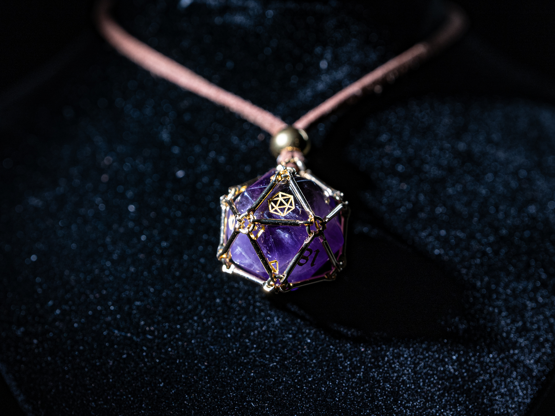 Angled macro shot of “Saga – Arcane Focus”: purple Amethyst D20 inside a golden dice cage on a brown PU leather necklace.