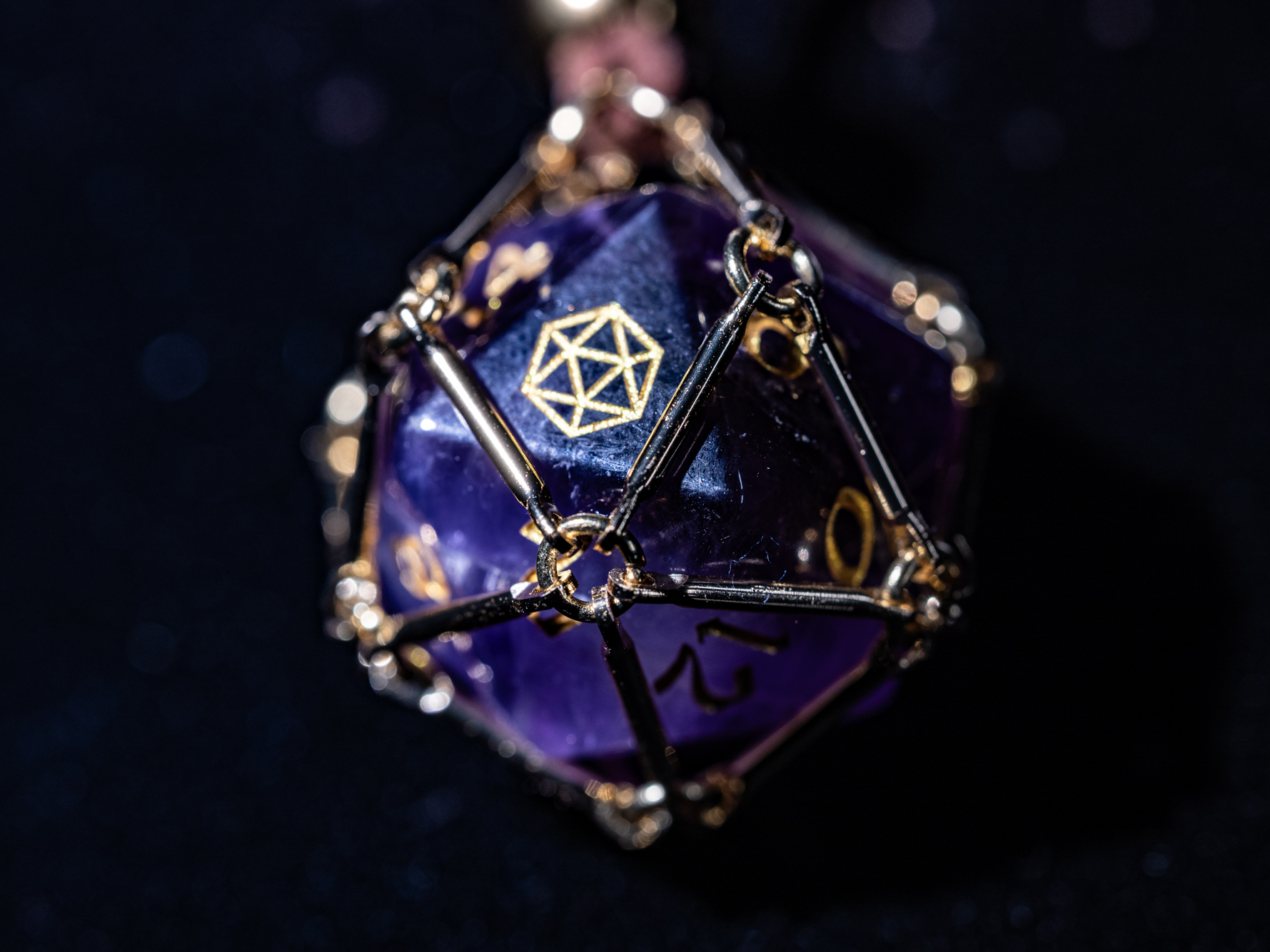 Angled macro shot of “Saga – Arcane Focus”: purple Amethyst D20 inside a golden dice cage on a brown PU leather necklace.