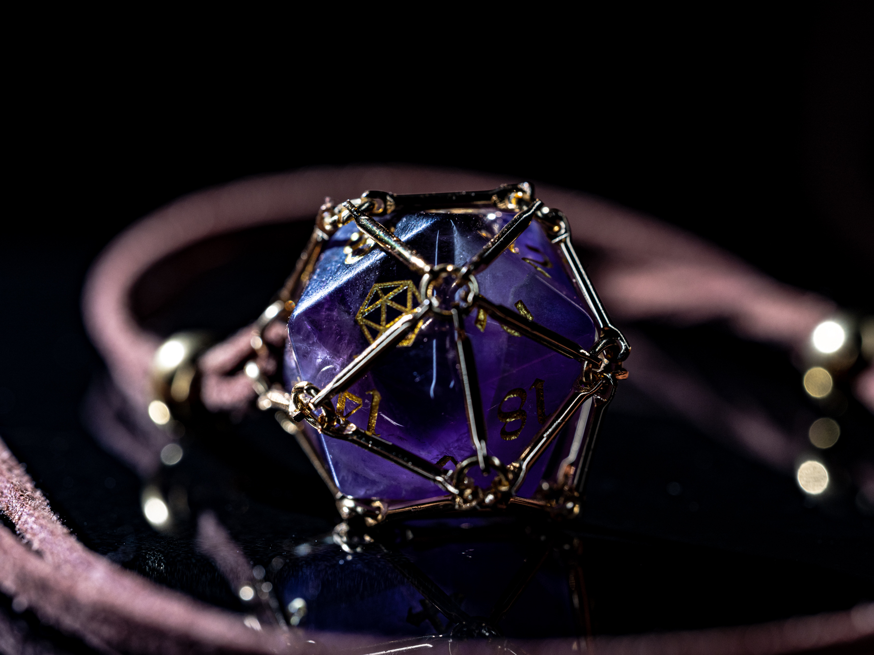 Angled macro shot of “Saga – Arcane Focus”: purple Amethyst D20 inside a golden dice cage on a brown PU leather necklace.